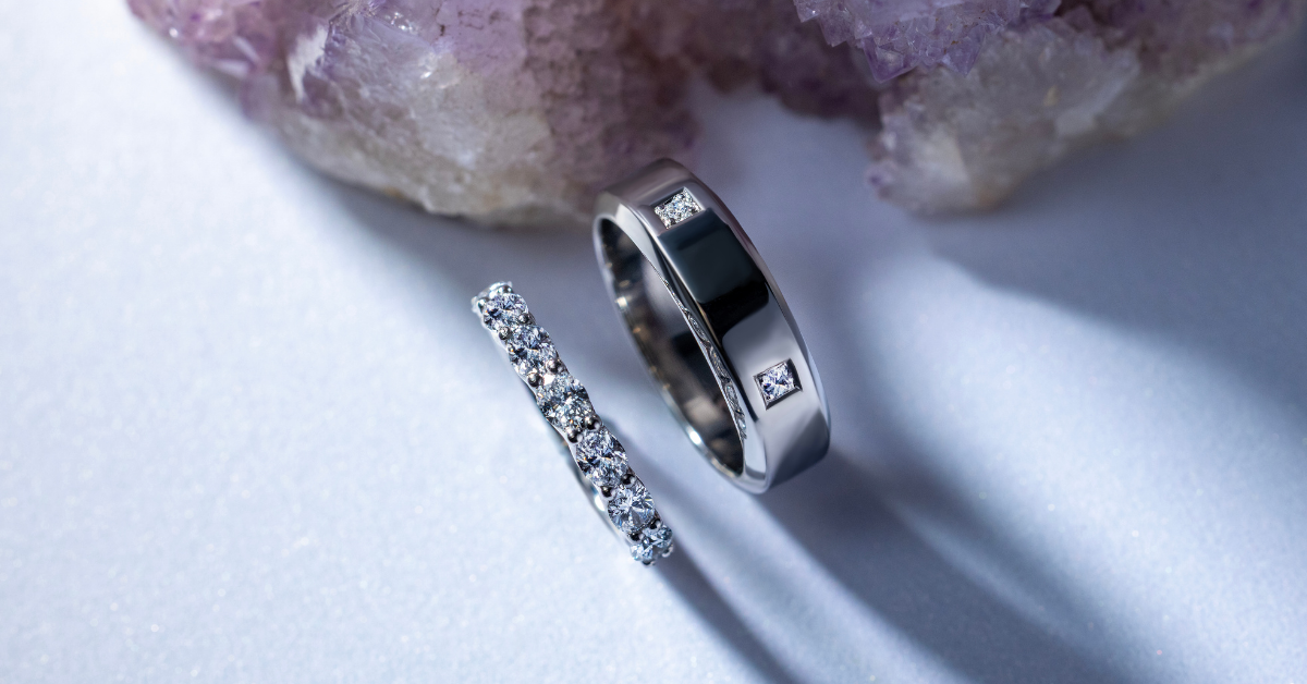 White Gold Diamond Wedding bands on a light surface with purple crystals in the background